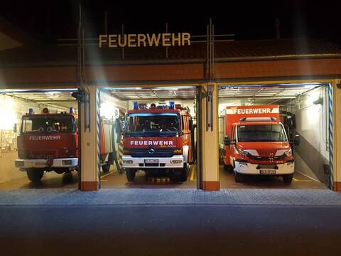 Drei Autos der Freiwilligen Feuerwehr Differten bei Nacht in ihren Garagen